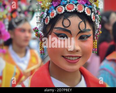 L'artista tailandese cinese in costume femminile con la maschera painted tradizionale dell'opera di Pechino sorride per la macchina fotografica durante la colorata sfilata cinese di strada di Capodanno. Foto Stock