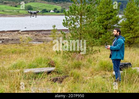 Pilota di droni dopo il decollo con un drone DJI nel Galloway Forest Park, Scozia - Regno unito - 15 settembre 2020 Foto Stock