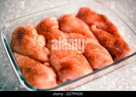 Filetti di pollo crudo con spezie in teglia da forno in vetro pronti per cucinare Foto Stock