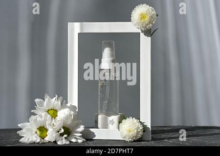 gel di collagene peptidato in flacone trasparente. struttura con fiori e flacone di prodotto cosmetico. gel per la cura del viso senza marchio. prodotto anti-età per la cura del viso e della bellezza. Foto Stock