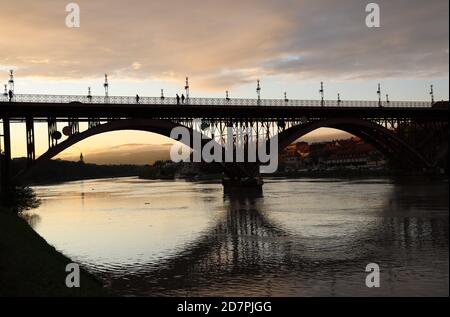 Persone che attraversano il Ponte Vecchio a Maribor al tramonto Foto Stock