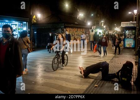 Barcellona, Spagna. 24 Ott 2020. A Las Ramblas di Barcellona un uomo si ostrada e chiede elemosine mentre i pedoni indossano maschere a piedi lungo il viale. La Spagna si avvicina ad un altro stato di allarme dopo che otto regioni hanno invitato il governo ad attuare la misura di emergenza per contrastare le infezioni da coronavirus. Credit: Jordi Boixareu/Alamy Live News Foto Stock