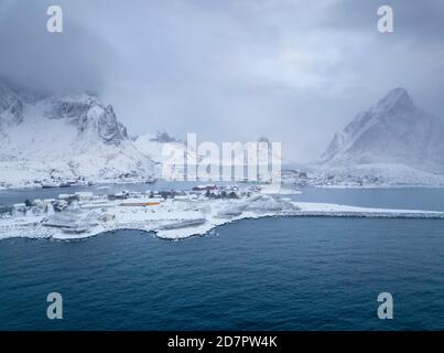 Atmosfera invernale sul fiordo nel villaggio di pescatori, nevicate in montagna, Reine, Nordland, Lofoten, Norvegia Foto Stock