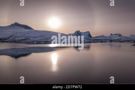 Anello del sole, alone sulla catena montuosa innevata, paesaggio artico invernale, in fronte mare, ballangen, Nordland, Norvegia Foto Stock