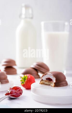 Teacakes di morbido centro di marshmallow fusion, ripieno di confettura di fragole e cioccolato rivestito di latte sullo sfondo Foto Stock