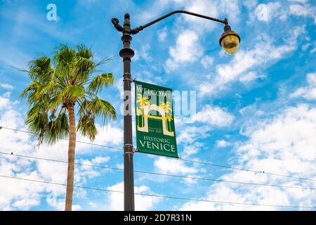 Venezia, USA - 29 aprile 2018: Cartello di benvenuto isolato sul palo della lampada nella piccola città della Florida nel golfo del Messico con palme e nuvole nel cielo Foto Stock