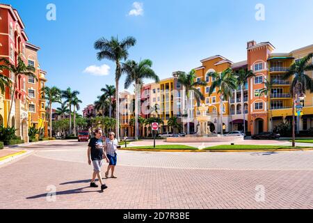 Napoli, USA - 30 aprile 2018: Condomini fronte baia colorati edifici multicolore con fontana d'acqua, persone candite sulla strada e palme Foto Stock