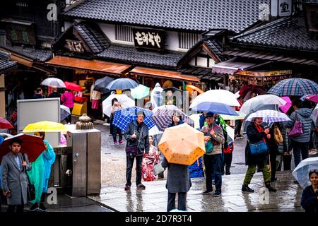 Kyoto, Giappone - 10 aprile 2019: Molte persone turisti con ombrelloni a piedi durante il giorno piovoso per strada vicino al tempio Kiyomizu-dera Foto Stock