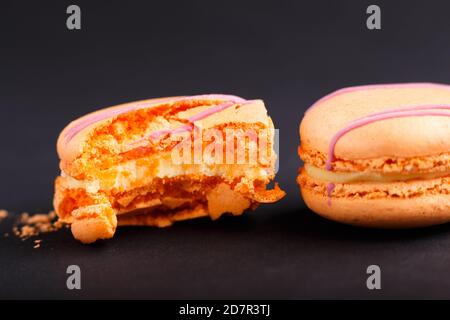 Macaroni interi e amaretti o torte di amaretti su sfondo nero. Vista laterale, primo piano, macro, fuoco selettivo. Foto Stock