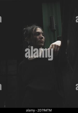 Foto verticale ad angolo basso di una donna meditata vestita tutto nero guardando da parte Foto Stock