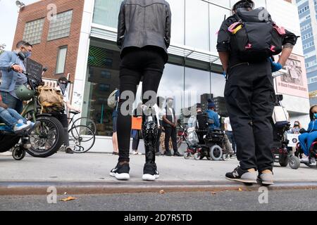 New York, New York, Stati Uniti. 24 Ott 2020. KIARA MARSHALL, 28 di Brooklyn, New York prepara gli stand di fronte allo Schomburg Center for Research in Black Culture mentre lei e altri si preparano a marciare in una protesta contro la questione Black Disabled Lives a New York, New York. La Marshall ha perso la gamba destra a causa di un incidente di guida ubriaco quando aveva dieci anni. I manifestanti marciarono lungo le strade di Harlem verso il parco Marcus Garvey e diedero discorsi sulla vita dei disabili. Credit: Brian Branch Price/ZUMA Wire/Alamy Live News Foto Stock