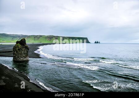 Myrdal, Islanda, vista ad alto angolo della spiaggia di sabbia nera di Reynisfjara e formazioni rocciose vulcaniche con la costa costiera e le onde che si infrangono per rivivere Foto Stock