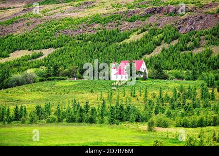 Vista panoramica del prato islandese a ovest di Akureyri durante giorno d'estate e verdi colline con erba rossa e. casa bianca e alberi Foto Stock