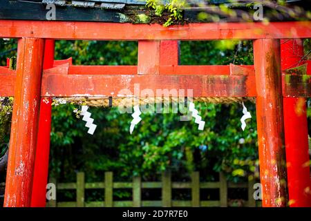 Kyoto, Giappone primavera giardino rosso Takenaka Inari Jinja Santuario torii cancelli percorso tempio ingresso e shide appeso carta ripiegata su corda Foto Stock