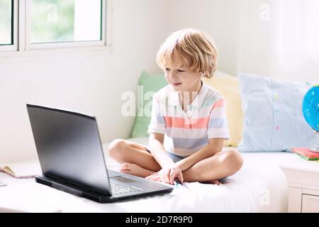 Apprendimento remoto online. Ragazzo di scuola con computer che ha videoconferenza chat con insegnante e gruppo di classe. Bambino che studia da casa. Ragazzo piccolo su essere Foto Stock