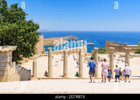 I turisti camminano lungo la scalinata che porta alle rovine stoa in cima all'acropoli di Lindos, Rodi, Grecia Foto Stock