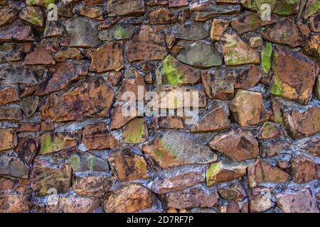 La vecchia struttura di muro di pietra accatastato hanno muschio verde luminoso lungo la roccia. Foto Stock