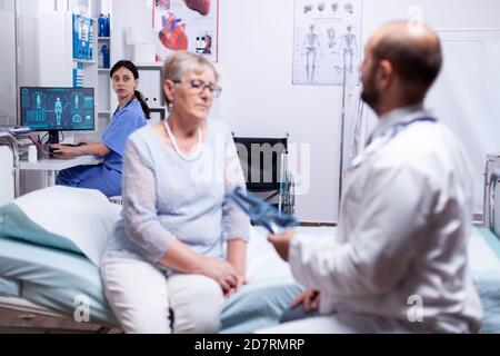 Donna anziana che ha una malattia polmonare contagiosa durante l'esame medico in sala d'ospedale con medico. Sistema medico sanitario, trattamento di prevenzione delle malattie, diagnosi di malattie. Foto Stock