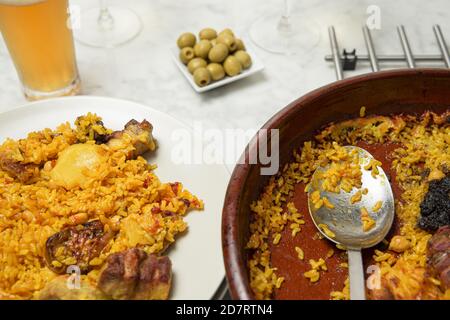 Paella, olive e un bicchiere di birra su un tavolo di marmo. Valencia, Spagna Foto Stock