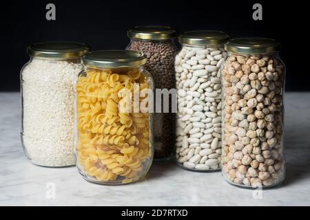 Set di vasetti di vetro con vari ingredienti posti su un piano di marmo. Concetto di zero sprechi Foto Stock