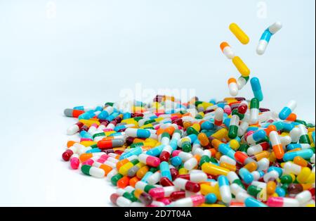 Fuoco selettivo su pila di pillole di capsula di antibiotico. Capsule di antibiotico colorate che cadono su tavola bianca. Concetto di resistenza agli antibiotici. Foto Stock