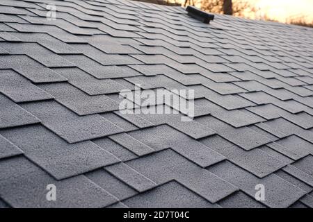 Primo piano su Asphalt Roofing Shingles background. Tegole - tetto. Frange del tetto coperte di brina Foto Stock