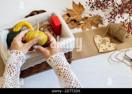 Le mani femminili che impaccano Halloween presenta zucche decorative e noci in scatola del regalo del mestiere. Idee di shopping etiche, eco-friendly e concetto fai da te. Foto Stock