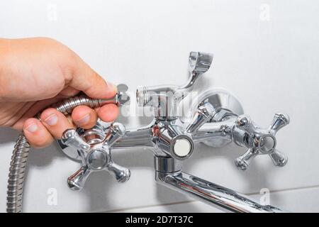 Idraulico ripara un rubinetto della doccia nel bagno. Foto Stock