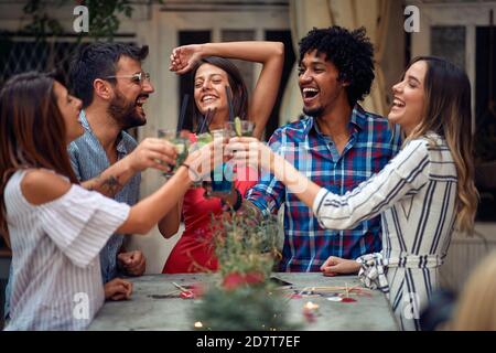 Coppie allegre che brinda alla festa di compleanno all'aperto in un bellissimo tramonto estivo. Tempo di amicizia di qualità insieme Foto Stock