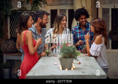 Amici allegri che si godono un colloquio alla festa di compleanno all'aperto su un bellissimo tramonto estivo. Tempo di amicizia di qualità insieme Foto Stock