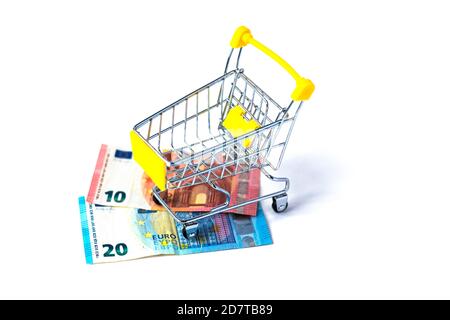 Piccolo carrello pieno di euro in contanti su sfondo bianco. Trenta euro in carrello giallo. Concetto di spesa e shopping. Isolato. Foto Stock