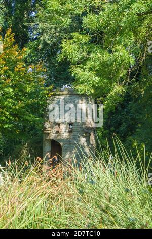 La torre dell'acqua di pietra che spouting l'acqua da un gargoyle, Westonbury Mill Water Gardens, Herefordshire UK. Settembre 2020 Foto Stock