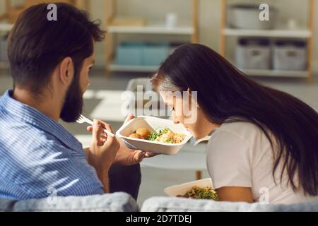 Giovane coppia gustando un pasto fresco e sano da asporto che hanno ordinato servizio di consegna cibo Foto Stock