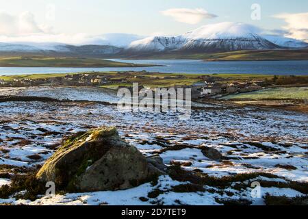 Vista dalla collina sopra la città scozzese Stromness in inverno. Colline dell'isola di Hoy coperte di neve e oceano Atlantico sullo sfondo