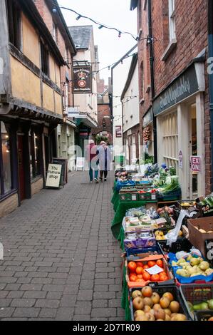 Intorno al Regno Unito - una coppia anziana che cammina davanti ad un negozio di greengrocers a Ludlow, Shropshire Foto Stock