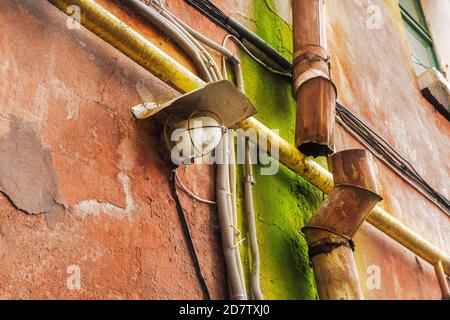 immagine di una lanterna e di un tubo di raccolta arrugginito sul muro di una casa Foto Stock