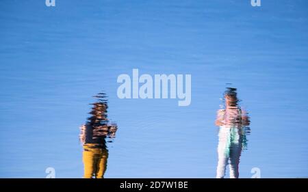 Riflessione di due giovani donne in piedi, in un lago d'acqua, in una giornata di sole Foto Stock