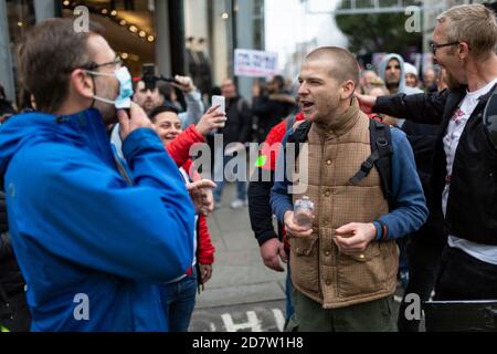 Un protestore si scontra con un astante sulla maschera indossata durante un rally anti-lockdown a Londra, 24 ottobre 2020 Foto Stock