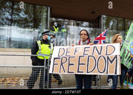 Un manifestante tiene un cartello di fronte alla polizia fuori New Scotland Yard durante un rally anti-lockdown a Londra, 24 ottobre 2020 Foto Stock