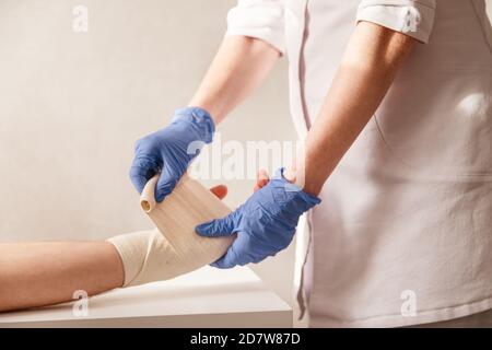 Il medico impone un bendaggio elastico al polso del paziente. Riabilitazione dopo la pioggia Foto Stock