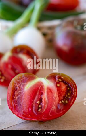 Preparazione di insalata verde fresca con grossi pomodori raddison-porpora Crimea nera Foto Stock