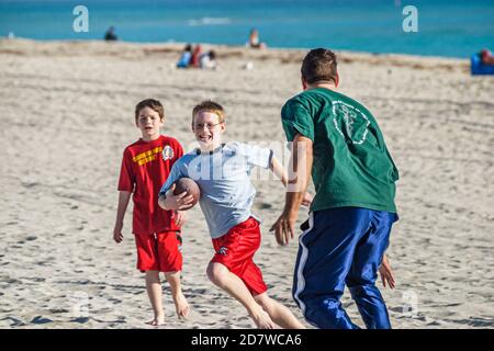 Miami Beach Florida, costa dell'Oceano Atlantico, riva del litorale, ragazzi figli fratelli padre famiglia giocare a calcio pubblico sport di sabbia vacanza, Foto Stock