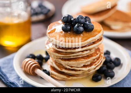 Gustosi pancake con miele e mirtilli su un piatto. Frittelle di grano integrale Foto Stock