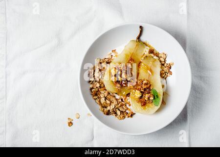 Pera in camicia con yogurt, noci e granola di avena. Foto Stock