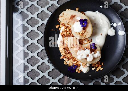 Pera in camicia con cannella, yogurt e granola di avena. Foto Stock