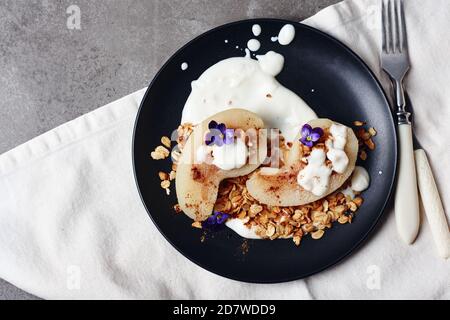 Pera in camicia con cannella, yogurt e granola di avena. Foto Stock