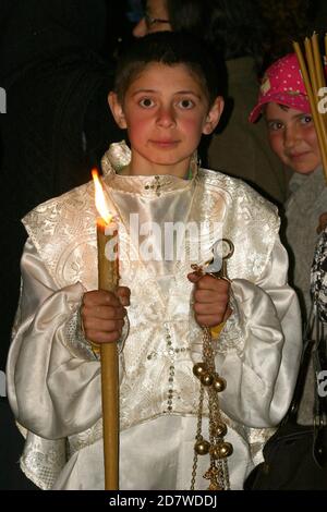 Servizio notturno di Pasqua all'interno di una chiesa cristiana ortodossa in Romania. Altare ragazzo che tiene la luce Santa e un tuono. Foto Stock