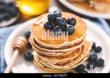 Pancake con mirtilli e vista del miele closeup, immagine tonata Foto Stock