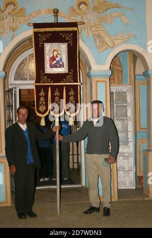 Tifesti, Contea di Vrancea, Romania. Uomini con una bandiera religiosa durante il servizio notturno di Pasqua della chiesa cristiana ortodossa. Foto Stock