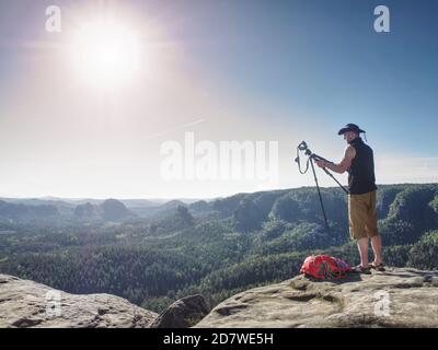 Treppiede da escursionista Cowboy con fotocamera sulla cima della montagna sopra il canyon. L'uomo con cappello da cowboy in pelle ascolta il suono della natura pura. Foto Stock